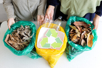 Top View Of Hands Holding Bags Of Separated Waste Shredded Paper, Plastic Bottles And Dry Leaves