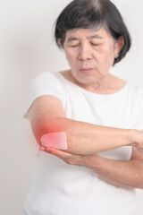 Elderly Woman having elbow ache with Medicated pain relief patch plaster for concepts of Tennis...