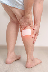 Elderly woman having Calf pain with Medicated pain relief patch plaster for concepts of Calf Muscle Strain, muscle pull, Leg Cramp, Sprain, aches, Varicose Veins, Deep Vein and world Thrombosis day