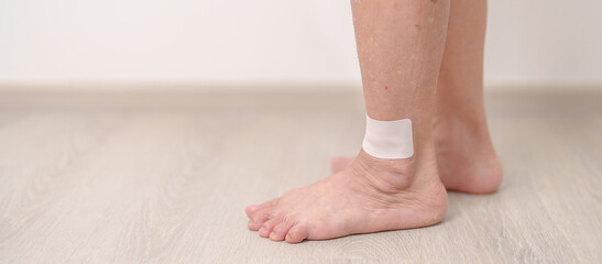 Elderly woman having leg pain with Medicated pain relief patch plaster for Ankle Sprains or Achilles Tendonitis and Shin Splints ache. injury, hyperuricemia disease, Gout and Senior Health care