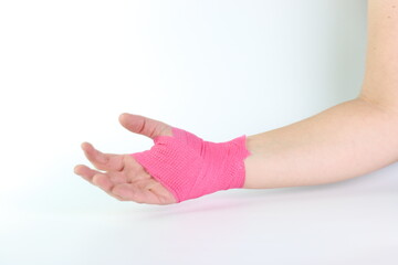 Woman hand with a pink cohesive bandage isolated in a white background