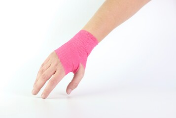 Woman hand with a pink cohesive bandage isolated in a white background