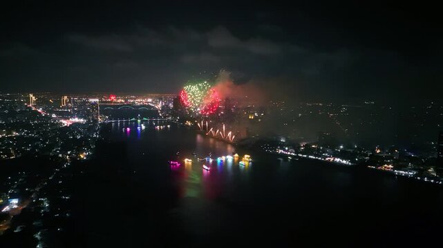 Colorful fireworks light up the night sky over illuminated boats cruising along the han river, creating a vibrant spectacle in da nang, vietnam