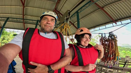 Smiling couple in harness ready for zipline experience at jungle platform in Bohol, Philippines Couple posing at zipline station in Bohol before adventure ride in tropical nature - Powered by Adobe