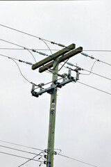 A wooden utility pole with multiple power lines against a grey sky, showcasing essential...