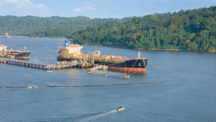 Cilacap oil tankers are moored at a busy port near Nusakambangan Island hills.
