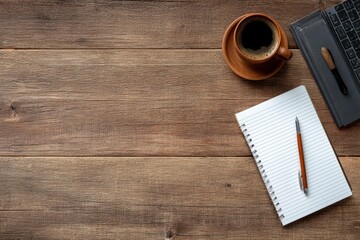 Overhead shot of a wooden desk with a coffee mug notepad pen and laptop