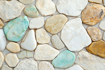 A textured arrangement of smooth river stones in various earthy tones and teal hues