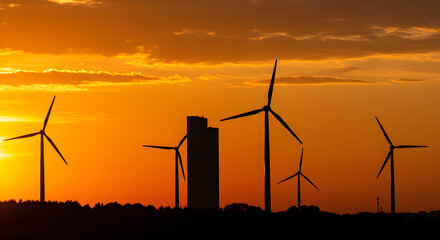Silhouetted Wind Turbines at Sunset with Modern Building