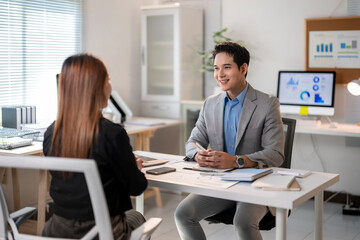 A man and a woman are sitting at a desk in a business setting