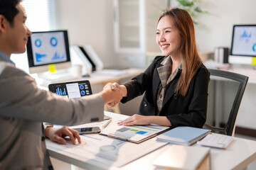 A woman shakes hands with a man in a business setting