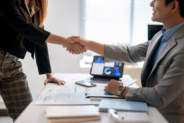 A man shakes hands with a woman in a business setting