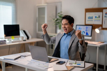 A man is sitting at a desk with a laptop and a cell phone
