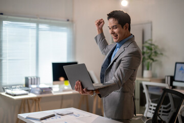 Naklejka premium A man in a suit is holding a laptop and smiling