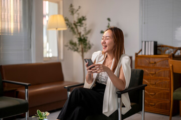 Fototapeta premium A woman is sitting in a chair with a cell phone in her hand