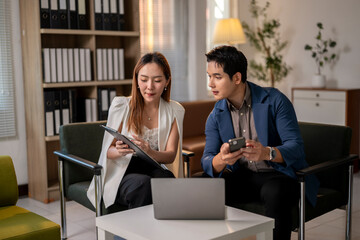 Two people are sitting on a couch and looking at a laptop