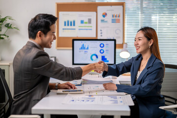 A man shakes hands with a woman in a business meeting