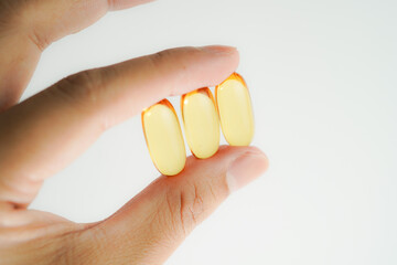 Male hand holding Fish oil capsules with omega 3, omega 9, vitamin D, vitamin E, Cod liver oil