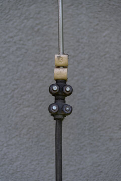Labeled down conductor for a lightning protection system, captured in natural outdoor light, showing the identification tag and its integration with the building&rsquo;s grounding infrastructure. 
