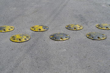Circular speed bumps on an asphalt road, captured in natural outdoor light, showing their raised...