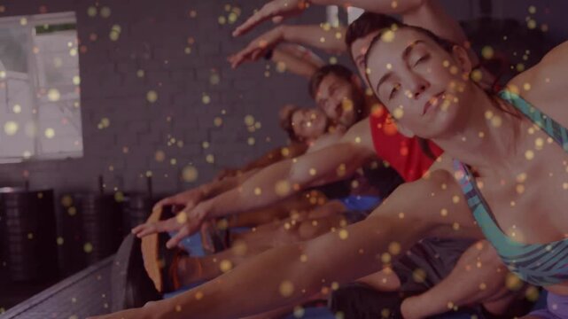 Instructor cueing breath engaging core, five Pilates group doing side-bend under glowing particles