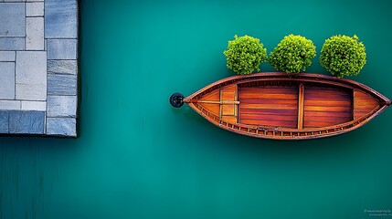 Minimalist zen garden arrangement: rowboat, topiary and stone set against teal backdrop