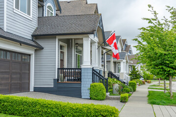 Two story stucco luxury house with Canadian flag in Vancouver, Canada, North America. Day time on...