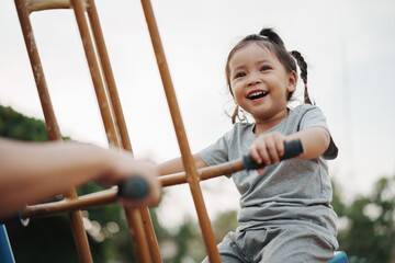 cheerful toddler girl playing on double swing with freind at outdoor playground