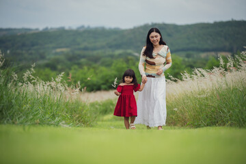 happy mother walking with her toddler girl on grass field