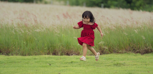 happy toddle girl in red dress running on grass field