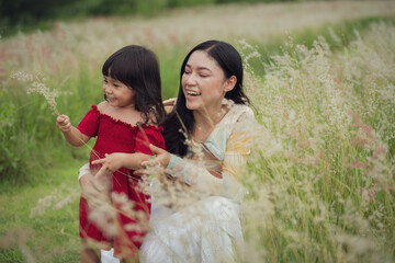 happy mother and daughter playing grass flower in field