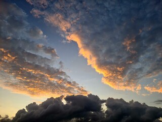 Dark thick clouds with soft upper layer lit by sunrise, contrasting textures of morning sky showing...