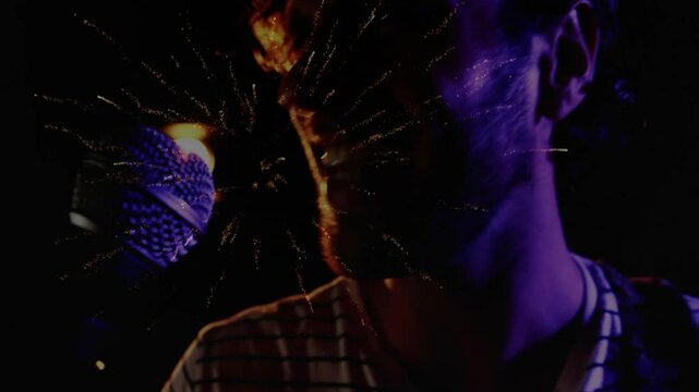 Male singer singing in purple lighting sparking fireworks bursting across mic showing music energy