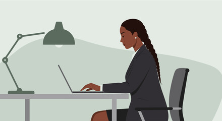 A young African American businesswoman is working on her laptop at her desk in a modern office, illuminated by a desk lamp, showcasing professionalism and focus.