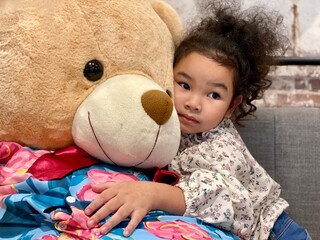 Little girl lying on sofa with teddy bear