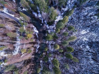 Aerial view of a river flowing through a snow-dusted forest near Yosemite National Park, USA. The...