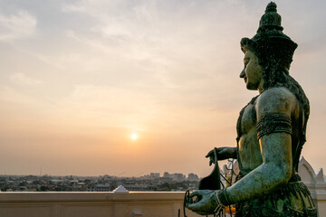 Fototapeta premium Giant statue overlooking bangkok at sunset from golden mount temple