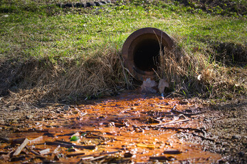 Rusty Drain Pipe Releasing Polluted Water Into Contaminated Soil in a Rural Outdoor Environment