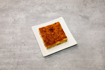Mexican budin de pan con pasas (bread pudding with raisins) on a white dessert plate.