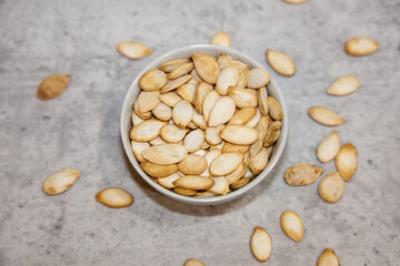 Unhulled pumpkin seed in a small bowl.