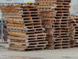 Stalked used wooden pallets outside a warehouse.