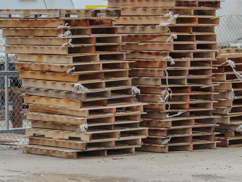 Stalked used wooden pallets outside a warehouse.