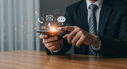 Businessman in Dark Suit Using Smartphone Interacting with Digital Icons Over a Wooden Table