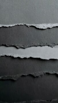 Dark gray handmade textured paper layers with ripped uneven edges, abstract neutral monochrome background pattern of rough cut cardboard