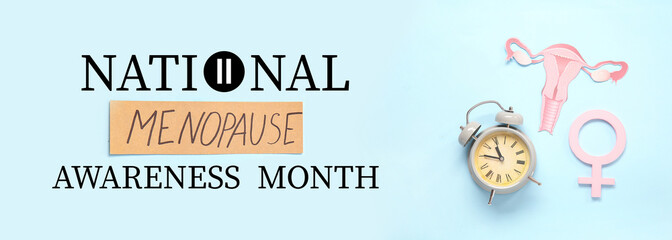 Word MENOPAUSE with paper uterus, alarm clock and symbol of woman on blue background