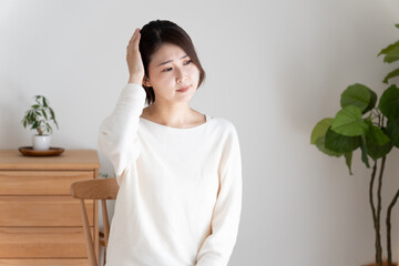 頭痛で頭を押さえる女性