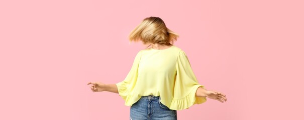 Stylish woman with short hair dancing on pink background