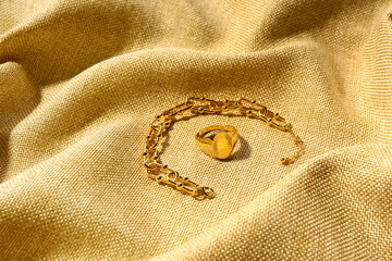 Beautiful chain bracelet and ring on beige fabric background