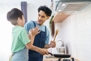 Asian man with young son are enjoy cooking together in kitchen at home in weekend.
