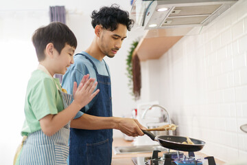 Asian man with young son are enjoy cooking together in kitchen at home in weekend.